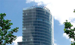 Moderní kancelářská budova v Brništi s velkými skleněnými okny a zakřiveným designem.